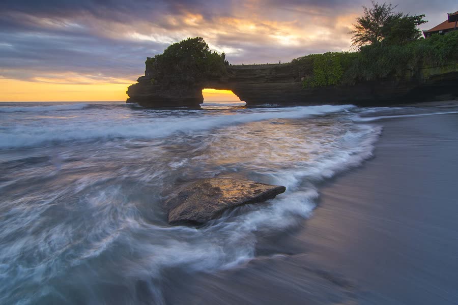 Sunset through the rock arch at Batu Bolong beach