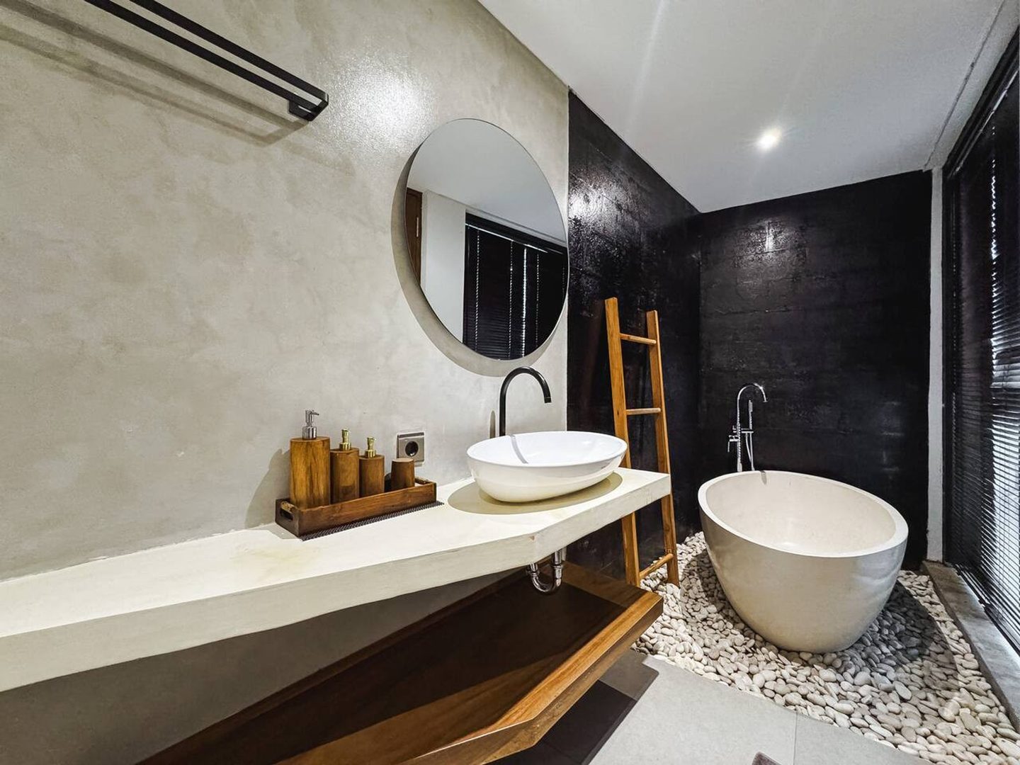 Twin basins on a stone shelf beside the freestanding tub