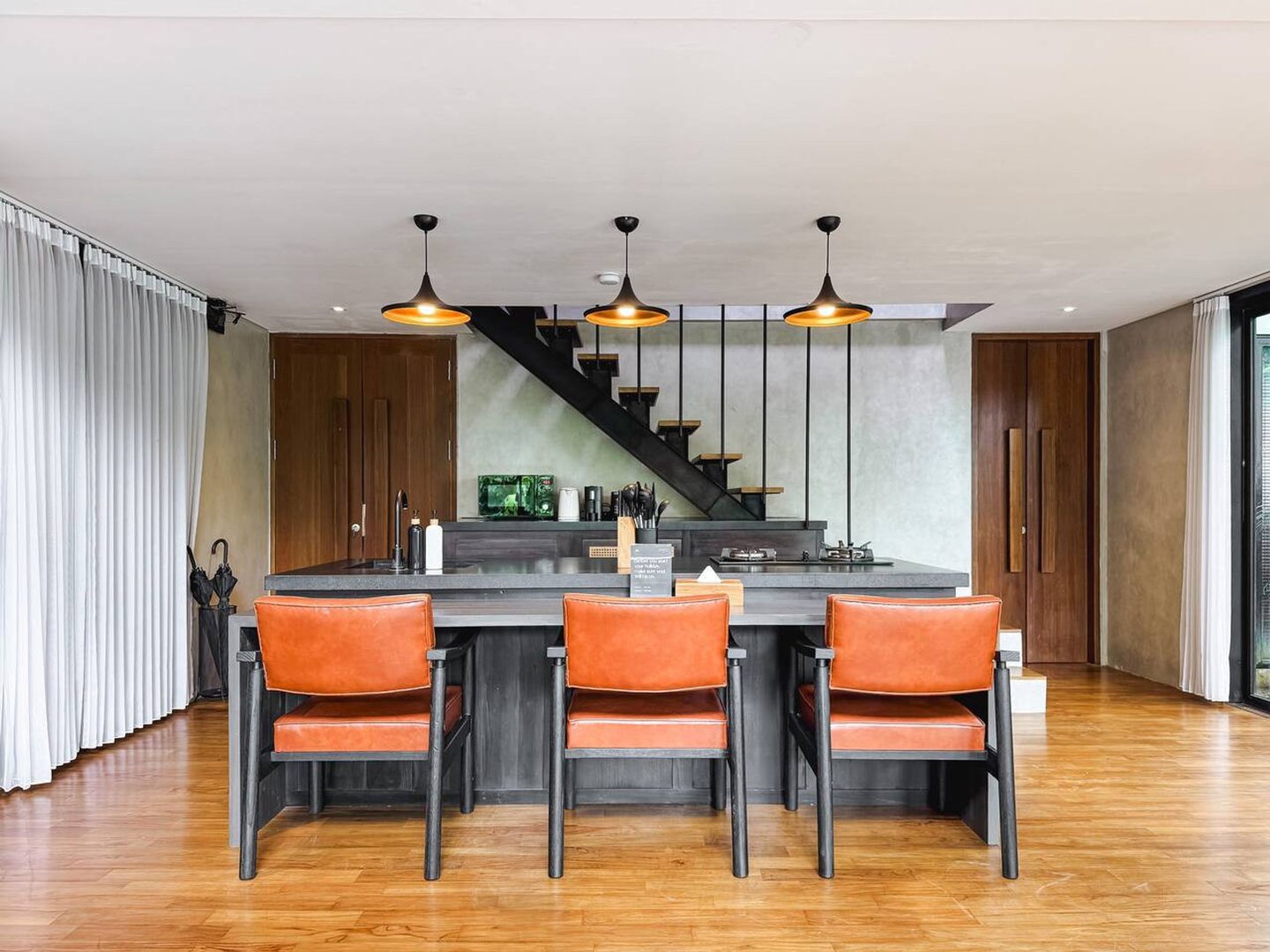 Kitchen counter with orange stools beneath pendant lights