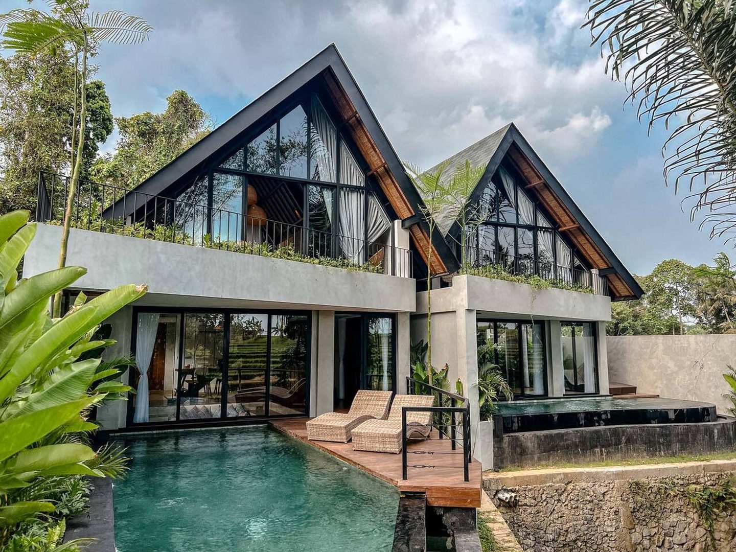 Twin woven gables above the pool under a bright sky