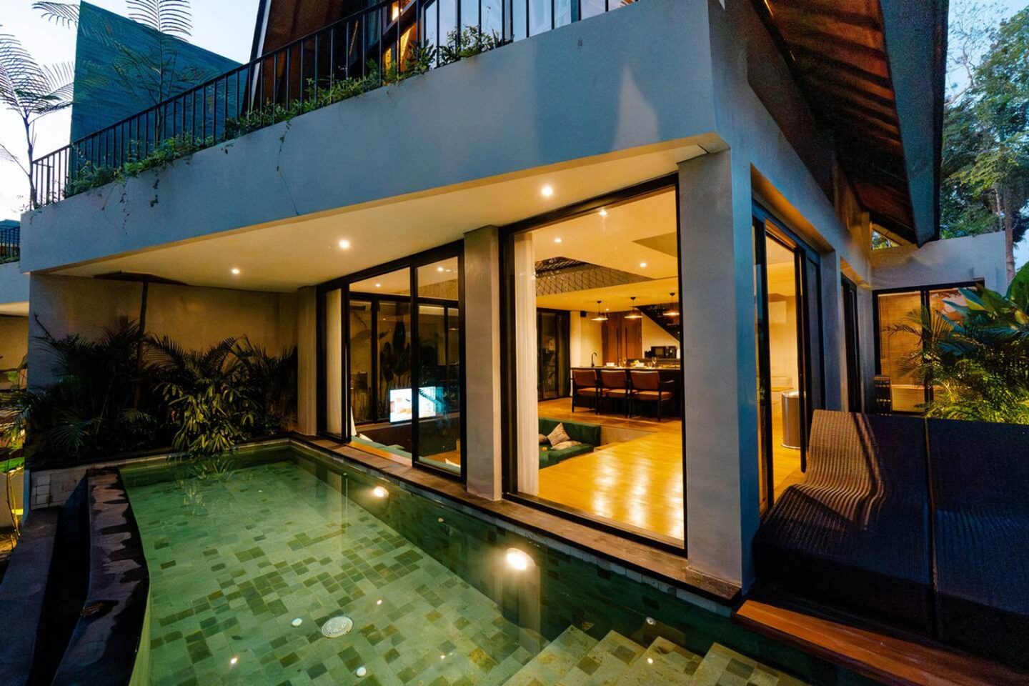 Villa Astu Two at dusk, the interior lit behind the glass