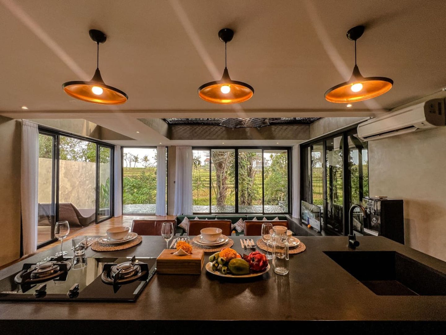 Island kitchen under warm pendants facing the paddies