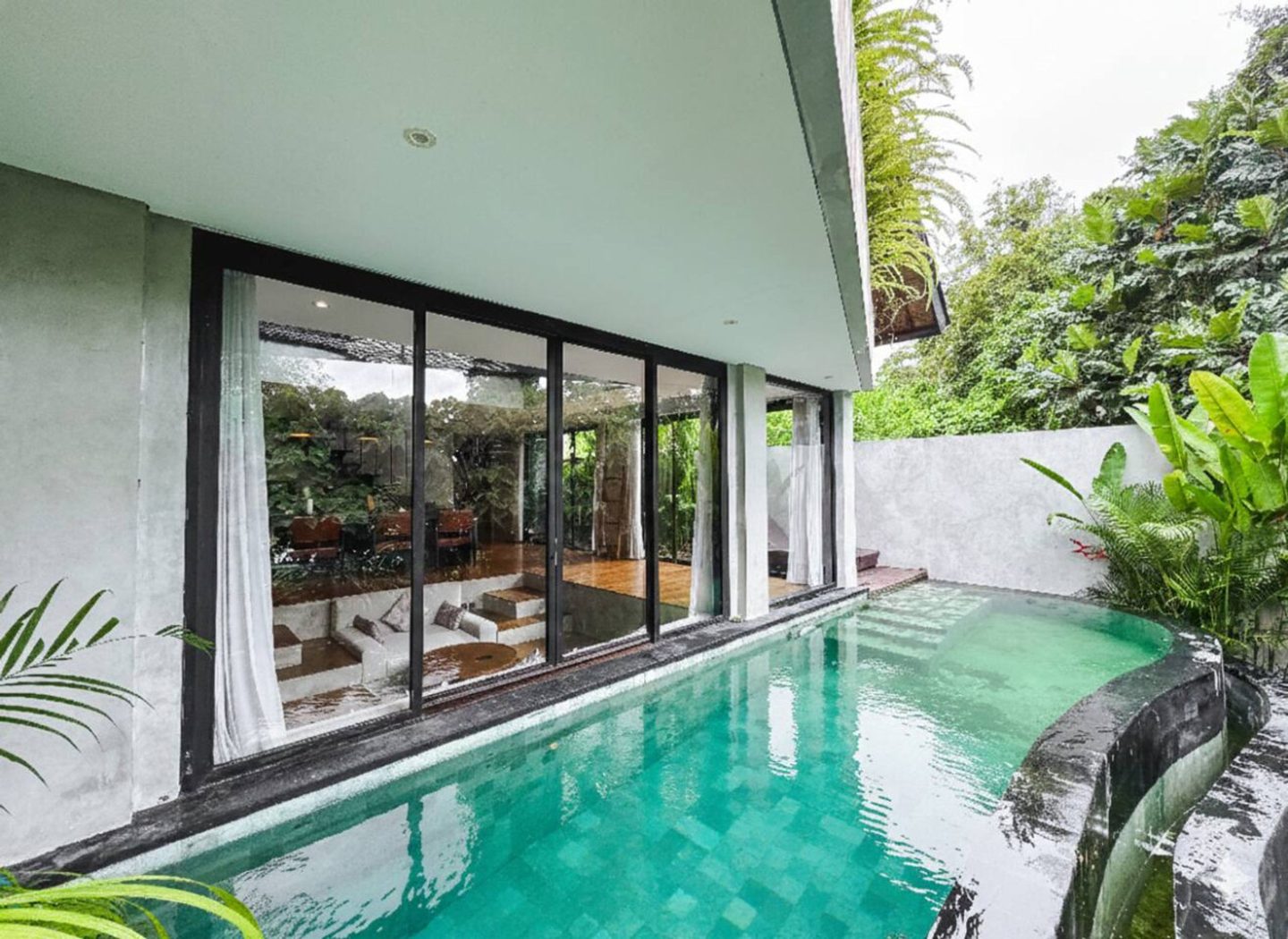 Green-tiled private pool running alongside the villa glass